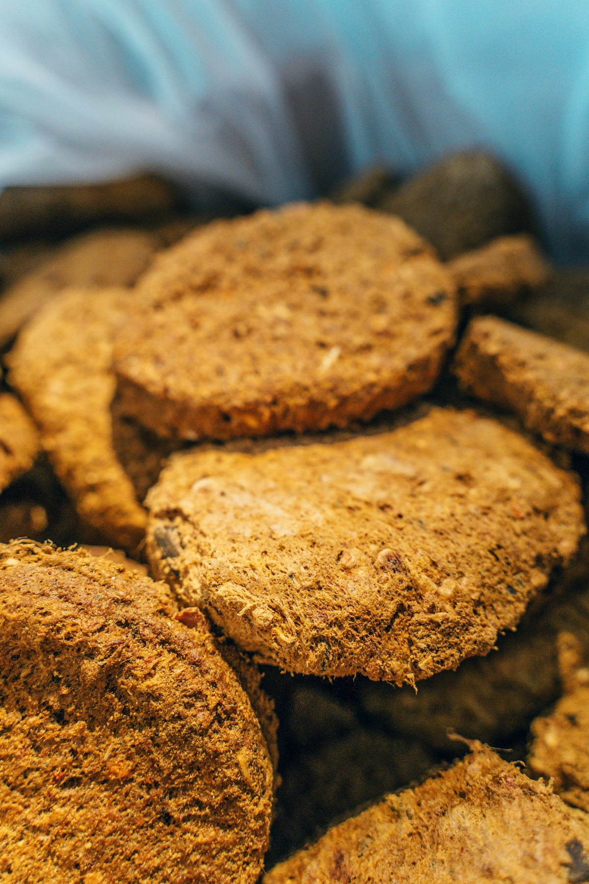 A close-up, top-down view inside a bag of Artisan Raw freeze-dried dog food, showing the fibrous texture and consistent shape of the raw meal pucks.