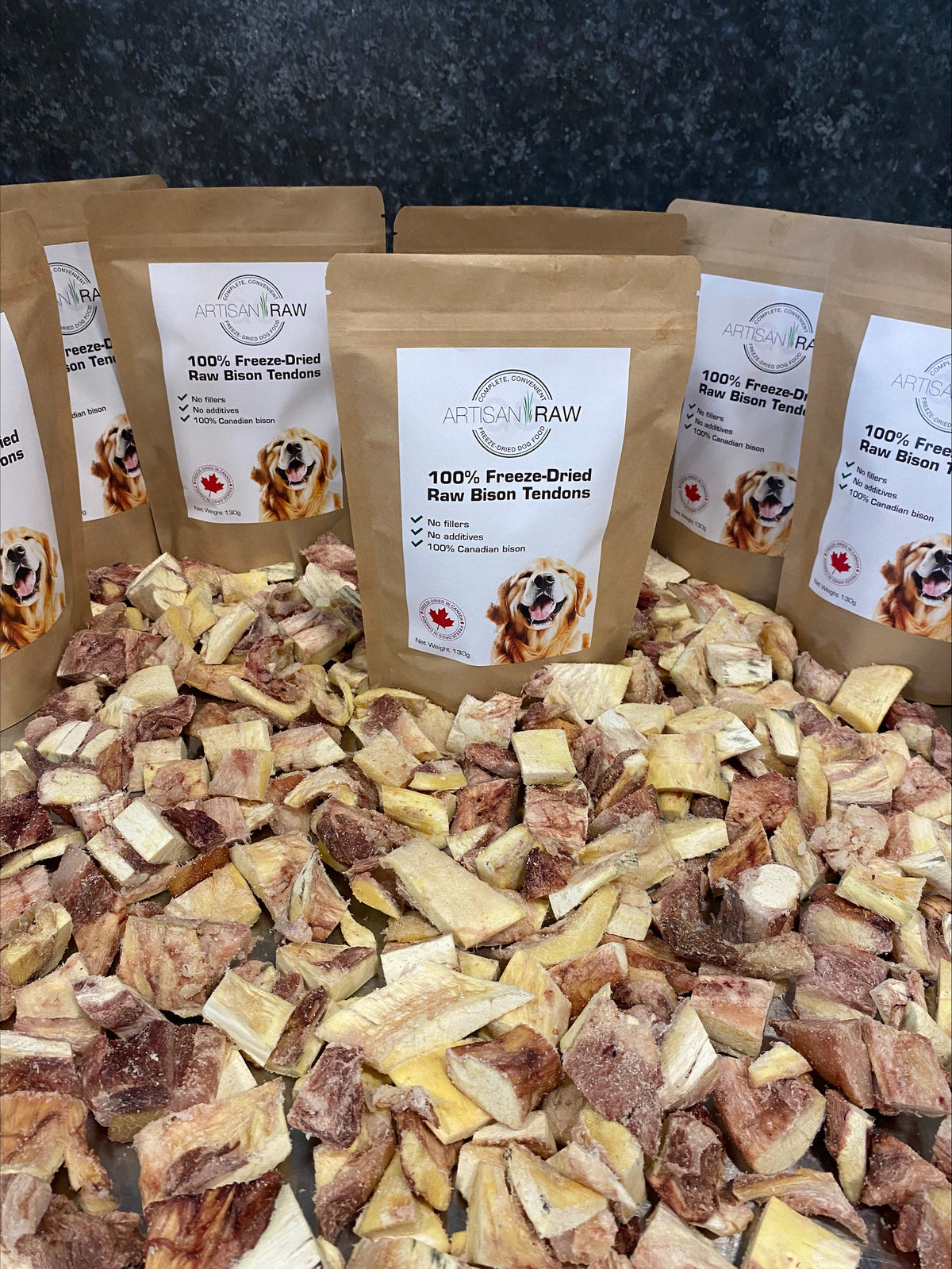 Artisan Raw GO! sampler box with freeze-dried raw bison tendons in brown packaging on a bed of dried meat pieces.